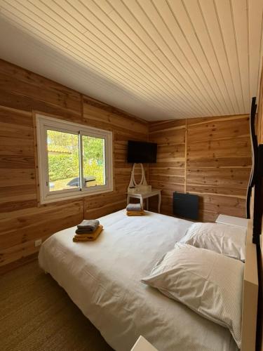 a bedroom with a white bed in a room with a window at La Maison de la forêt et son jaccuzy in Biscarrosse