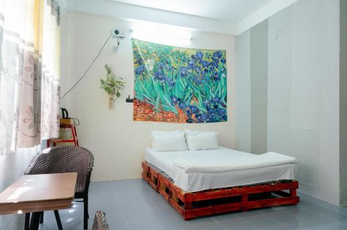 a bed in a room with a painting on the wall at Bụi Hostel - Ferry to Rạch Giá in Rach Gia