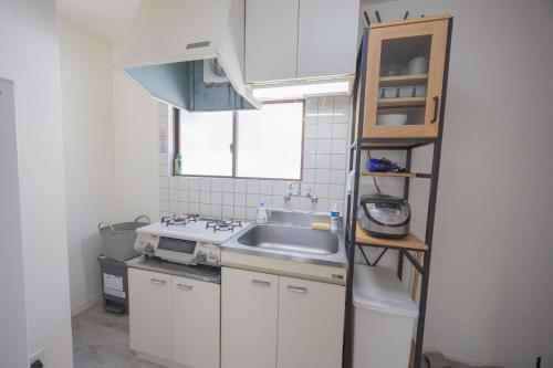 eine kleine Küche mit einem Waschbecken und einem Regal in der Unterkunft shan-Nishiochiai 2F in Tokio
