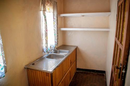 baño pequeño con lavabo y ventana en Okavango Lodge en Livingstone