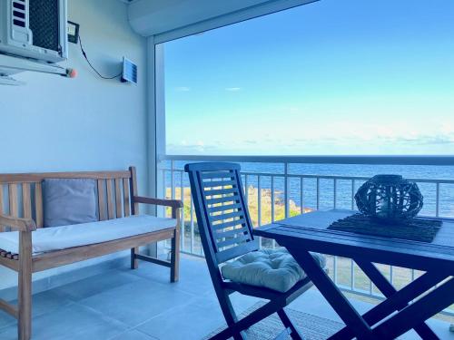 a table and chair on a balcony with a view of the ocean at Excellence Suites Orient Beach Oceanview King-Size Beach Pool Parking in Cul de Sac