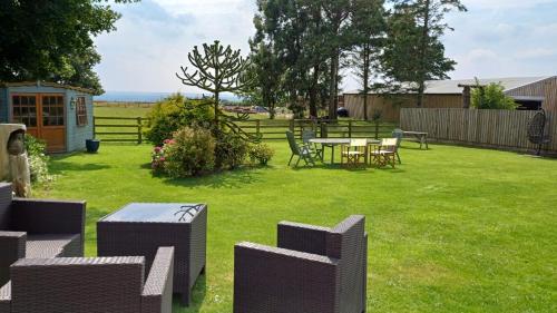 a yard with a table and chairs and a fence at Cottage Lea's Country Hotel & Restaurant in Pickering