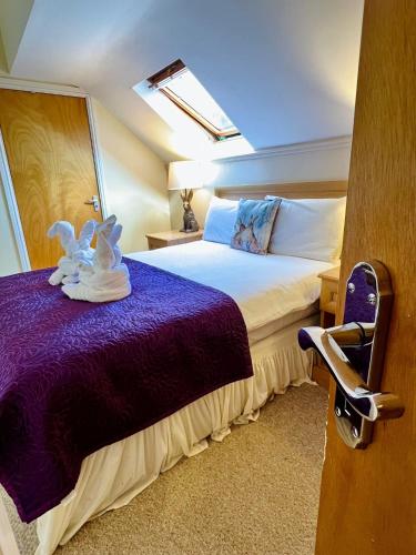 a bedroom with a large bed with a purple blanket at Cottage Lea's Country Hotel & Restaurant in Pickering
