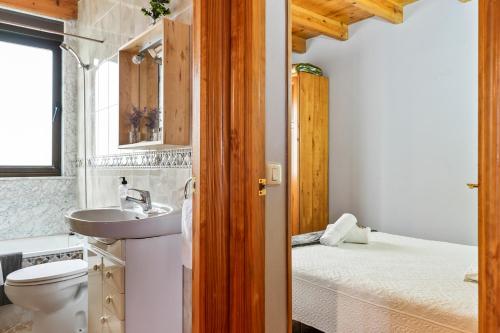 a bathroom with a sink and a toilet and a bed at Romano I megustarural in Porrúa
