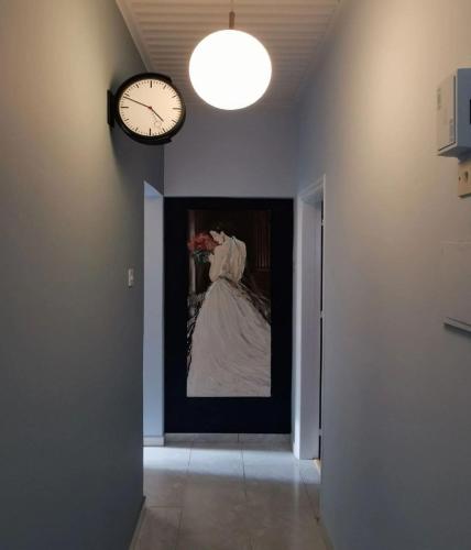 a clock on a wall with a painting of a woman at Larnaca Breeze in Pyla