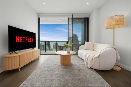a living room with a tv and a white couch at Starview Suite - Private Oceanview 2 Bedroom Apartment on the Star Residence Broadbeach, Free Carpark Included with your stay! in Gold Coast