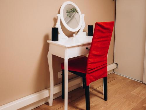 a red chair and a white dressing table with a mirror at Casa Di Vibes - Jacuzzi - Sauna in Saint-Maur-des-Fossés