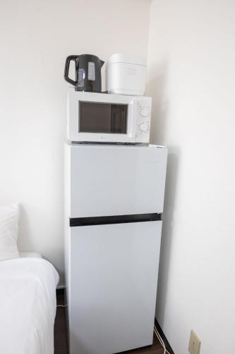 a microwave sitting on top of a white refrigerator at Palasto Hostel-SJ0002 in Tokyo
