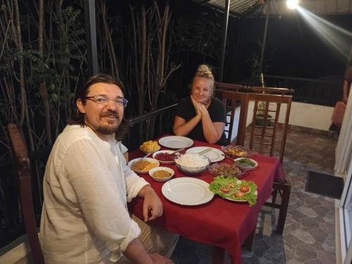 a man and a woman sitting at a table with food at Evergreen Cottage in Ella