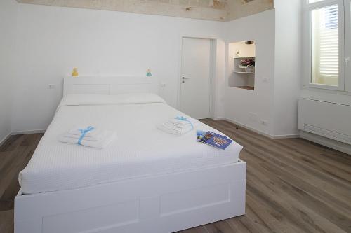 a white bed in a white room with two towels on it at LucAsia in Monopoli