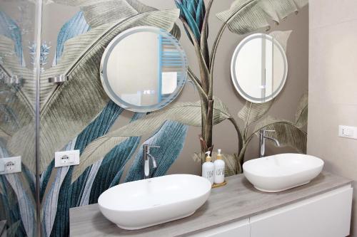 a bathroom with two sinks and mirrors on a wall at LucAsia in Monopoli