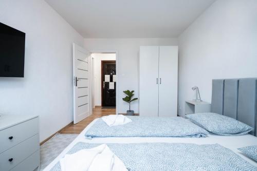 a white bedroom with two beds and a tv at Vyskoč na hory in Nová Lesná