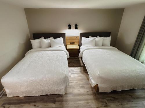 two beds in a hotel room with white sheets at The Earl of Sandwich Motel in East Sandwich