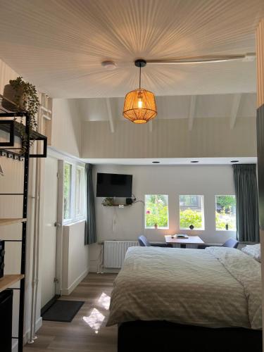 a bedroom with a bed and a table and windows at B&B De Dreef in Middelburg