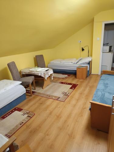 una habitación con dos camas y una mesa y sillas en Dékány vendégház, en Mezőhegyes