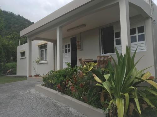 a white house with a porch and some plants at Villa Montjoly in Le Morne-Vert