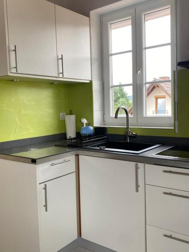 cocina con armarios blancos, fregadero y 2 ventanas en 3-Zimmer-FeWo Hexenhäusle Bollschweil, en Bollschweil