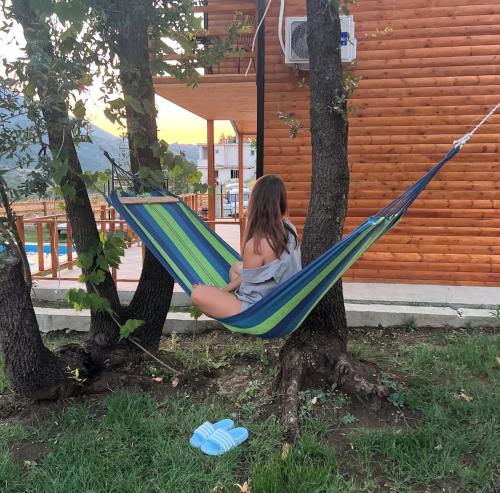 a woman sitting in a hammock in a tree at Green Oasis in Fshati i Ri