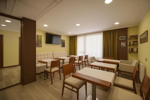 un ristorante con tavoli, sedie e una televisione di Elara MSuites a Viveiro