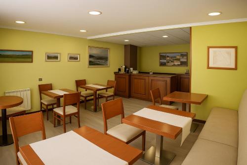 un ristorante con tavoli e sedie in una stanza di Elara MSuites a Viveiro