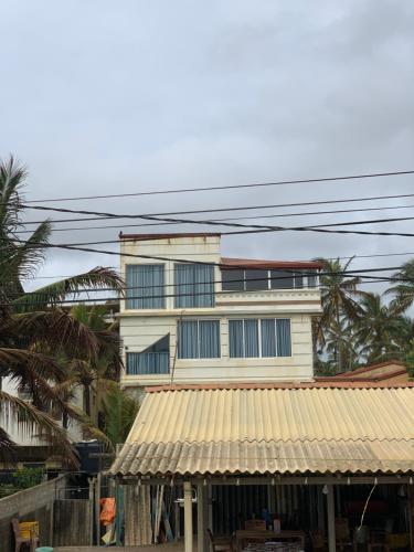 a tall white building with windows and a roof at Rodrigo Beach Villa in Uswetakeiyawa