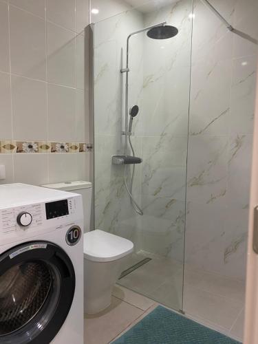 a bathroom with a shower with a toilet and a washing machine at Pebble Beach in San Miguel de Abona