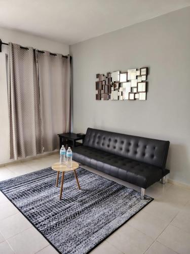 a black leather couch in a living room with a table at Casa Las Huertas Tranquilidad y Confort para ti in Chetumal
