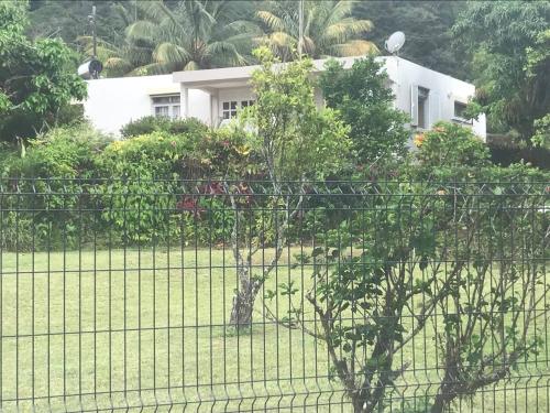 a fence in front of a yard with a house at Villa Montjoly in Le Morne-Vert