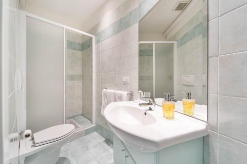 a white bathroom with a sink and a toilet at Green Village Accommodations in Colico