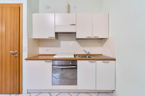 a kitchen with white cabinets and a sink at Green Village Accommodations in Colico
