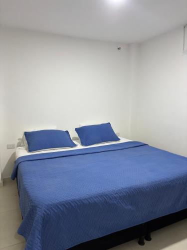 a blue bed with blue pillows in a white room at Los Médanos in Ríohacha