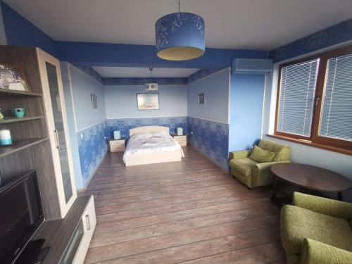 a bedroom with blue walls and a bed and a chair at Affordable Rooms with BBQ 5 min drive from beach Villa Lusi in Varna City