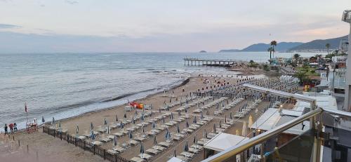 a beach with chairs and umbrellas and a pier at La Risacca in Pietra Ligure