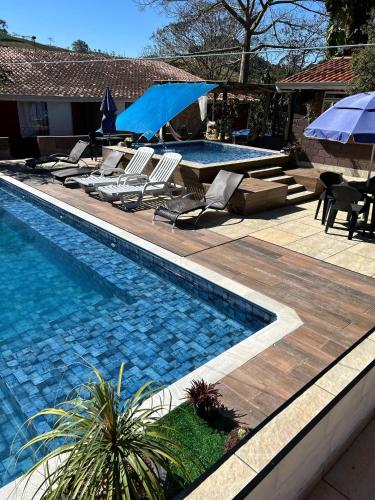 a swimming pool with chairs and umbrellas next to at Pousada Beija flor in Extrema