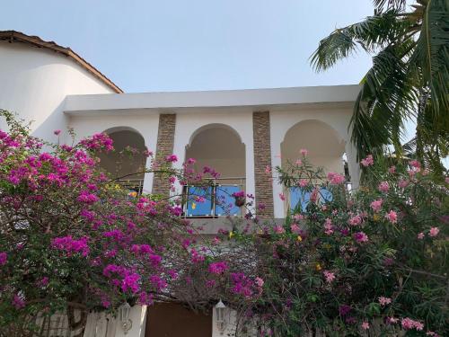 a house with pink flowers in front of it at Maison calme et fleurie in Cotonou