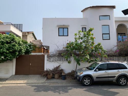 a silver car parked in front of a white house at Maison calme et fleurie in Cotonou