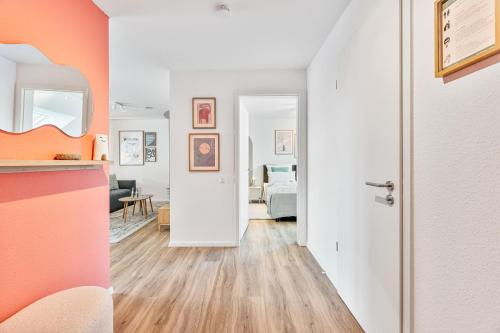 a living room with an orange accent wall and an open door at WHONAP - BLUVYN I Business I Parkplatz I Balkon I Natur in Walldürn