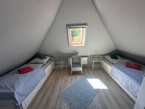 Un dormitorio abuhardillado con dos camas y una ventana. en Born 1A, en Born