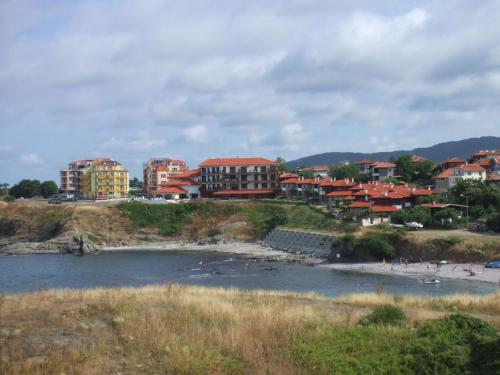 a group of buildings on a hill next to a body of water at Family Hotel Mimosa in Tsarevo