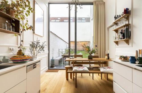a kitchen with white cabinets and a table and a window at Cozy Room with Garden in Brussels