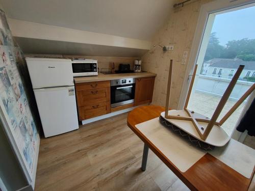 eine kleine Küche mit Tisch und Kühlschrank in der Unterkunft Bristol Manor N20 terrasse cuisine et chambre in Néris-les-Bains