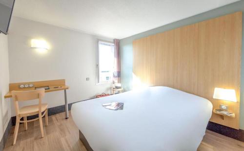 a bedroom with a large white bed and a desk at B&B HOTEL PERPIGNAN Nord Aéroport in Perpignan