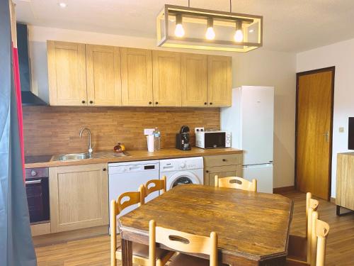 a kitchen with a wooden table and a table and a dining room at Appartement CERF in La Llagonne