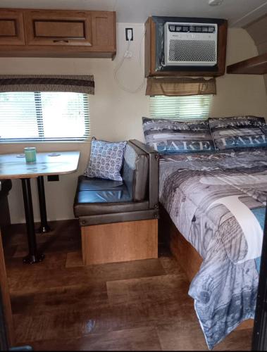 a bedroom with a bed and a couch and a table at Camper only 2 Min to the Lake! in Nancy