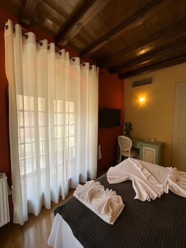 a bedroom with a bed with white curtains and a window at Archontiko Leontari in Leondari
