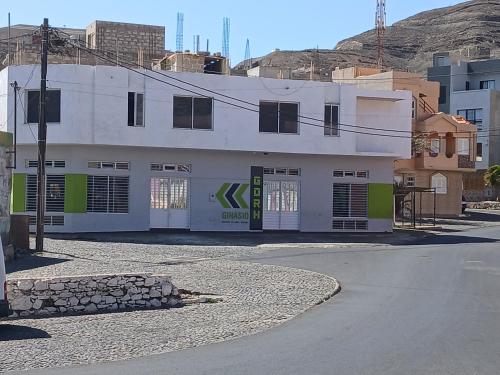 a white building with green accents on a street at Mar&Cruz in Mindelo