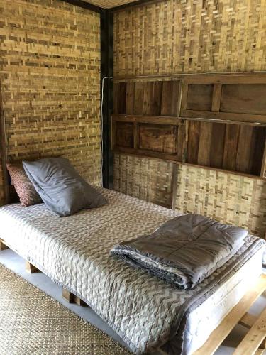 a bed in a room with a wooden wall at Sparrow Hut in Pai