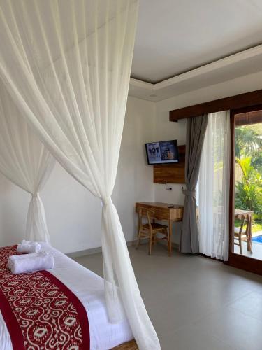 a bedroom with a bed with a curtain and a desk at Dukuh Sari Villa in Ubud
