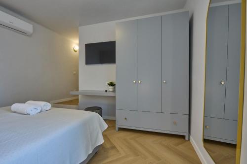 a white bedroom with a bed and a tv at CAMERANOAPARTMENTS - Sopra la Piazza in Camerano