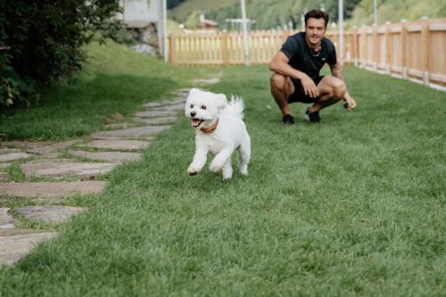 a man and a white dog running in the grass at Hotel Bergzeit in Grossarl
